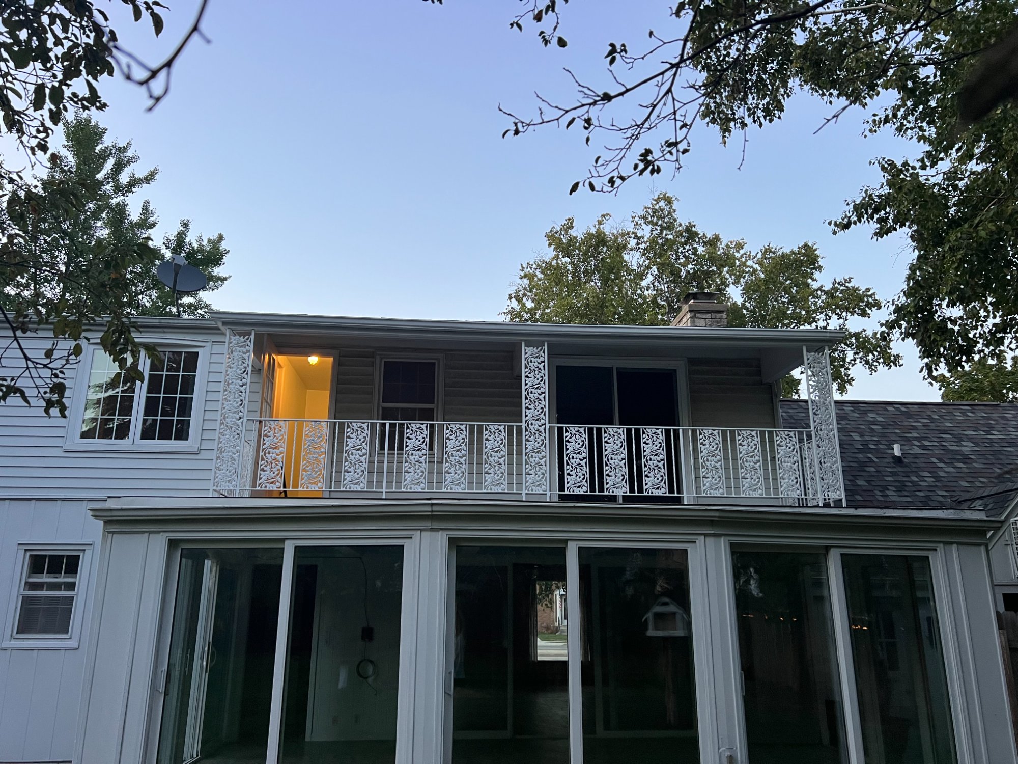Exterior of home at dusk showing freshly painted white decorative iron railing and second-floor balcony