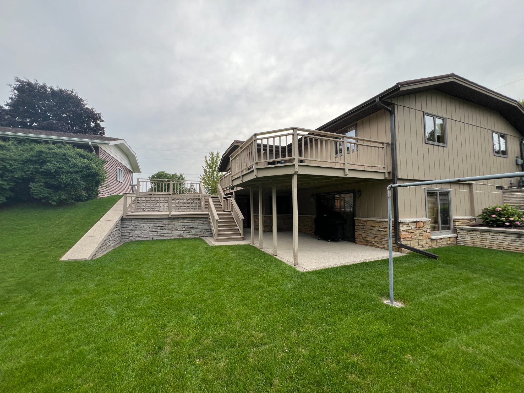 Alternate rear angle of ranch home showing painted siding, deck, and landscaped yard